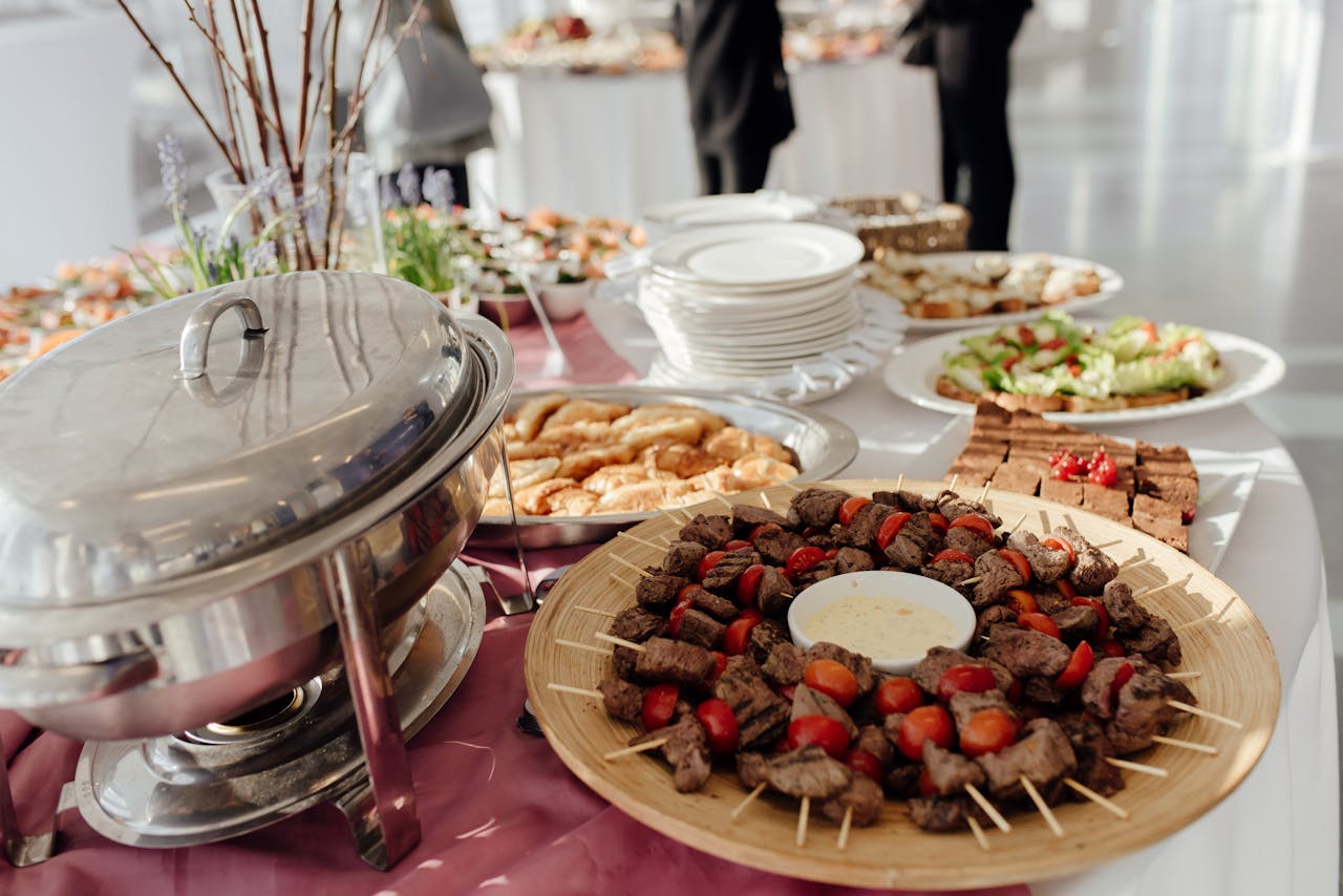 Elegant buffet featuring skewered meats, fresh salads, and assorted desserts at a festive event.